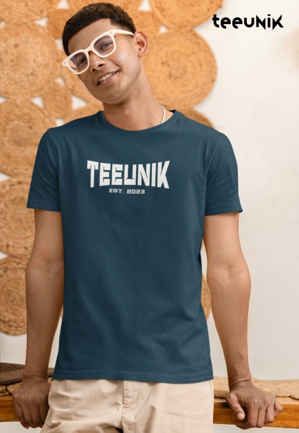 Casual lifestyle shot of a model wearing clear glasses, modeling a comfortable, standard-fit blue graphic tee with white Teeunik branding.