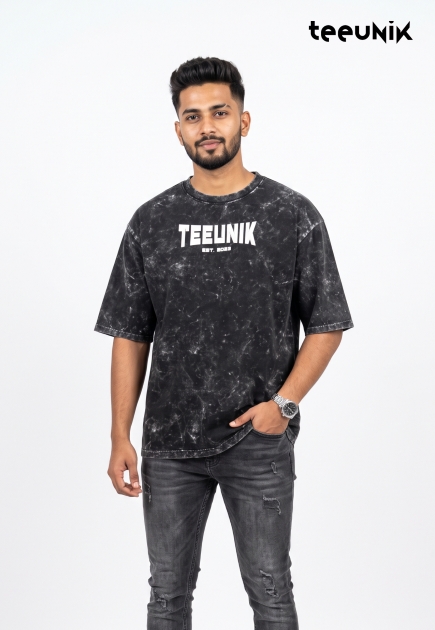 A black acid-wash streetwear t-shirt featuring a dropped shoulder design, relaxed fit, and the white TEEUNIK EST. 2023 logo.